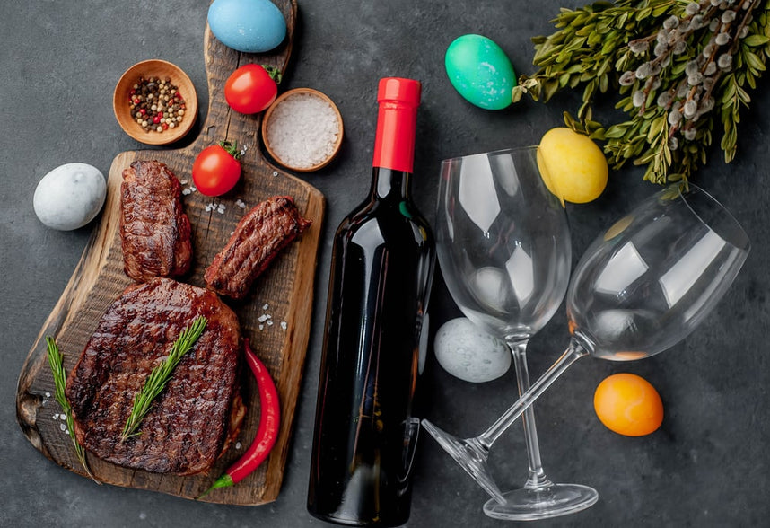 Grilled Easter steak with spices and a bottle of wine and glasses multi-colored eggs